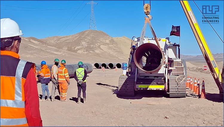 A group of construction workers gathered around a large pipe, discussing their project and inspecting the installation site.