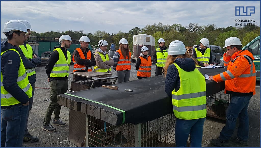 Eine Gruppe von Personen trägt Sicherheitswesten und steht zusammen in einem Arbeitsumfeld.