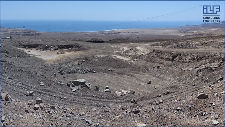 A large pit filled with rocks and dirt, set against the backdrop of a vast desert landscape.