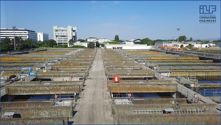 A large industrial area featuring numerous tanks and interconnected pipes against a clear sky.